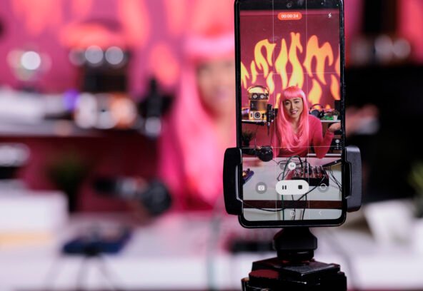 Influencer recording podcast using professional vlogging equipment while standing in streaming studio Influencer recording podcast using professional vlogging equipment while standing in streaming studio, posting vlog on social media to gain subscribers. Asian creator filming vlog with phone camera