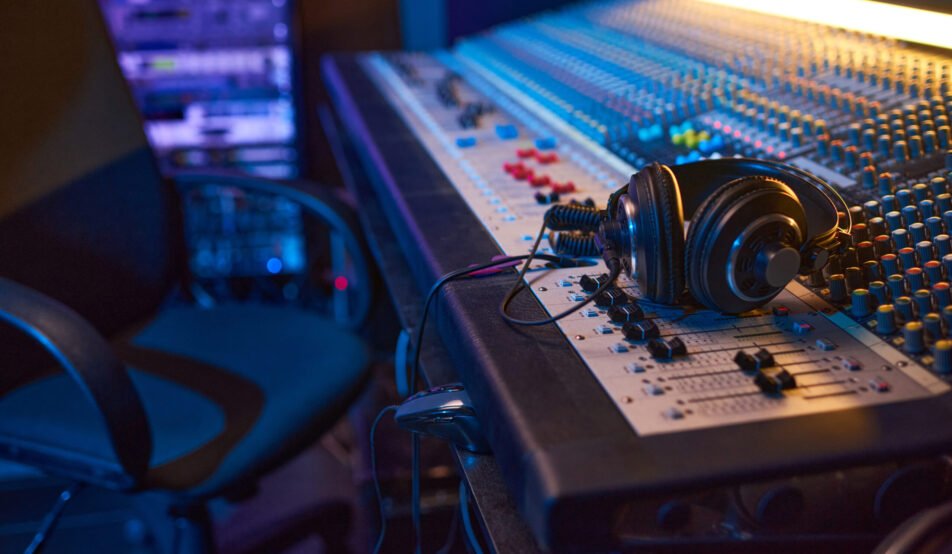 Close-up of sound mixing board with headphones on it for musical producer in studio